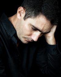 Dramatic close-up of a worried and depressed man isolated on black